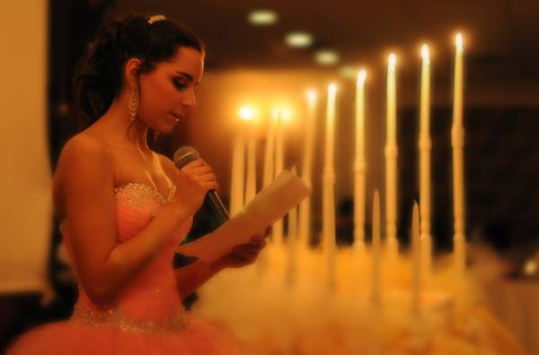 girl speaking in front of lit sweet 16 candles