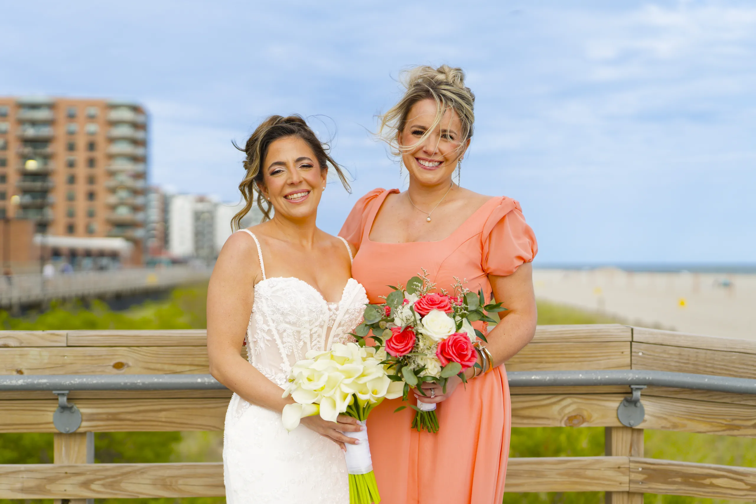 Bride and bridesmaid smiling outdoors